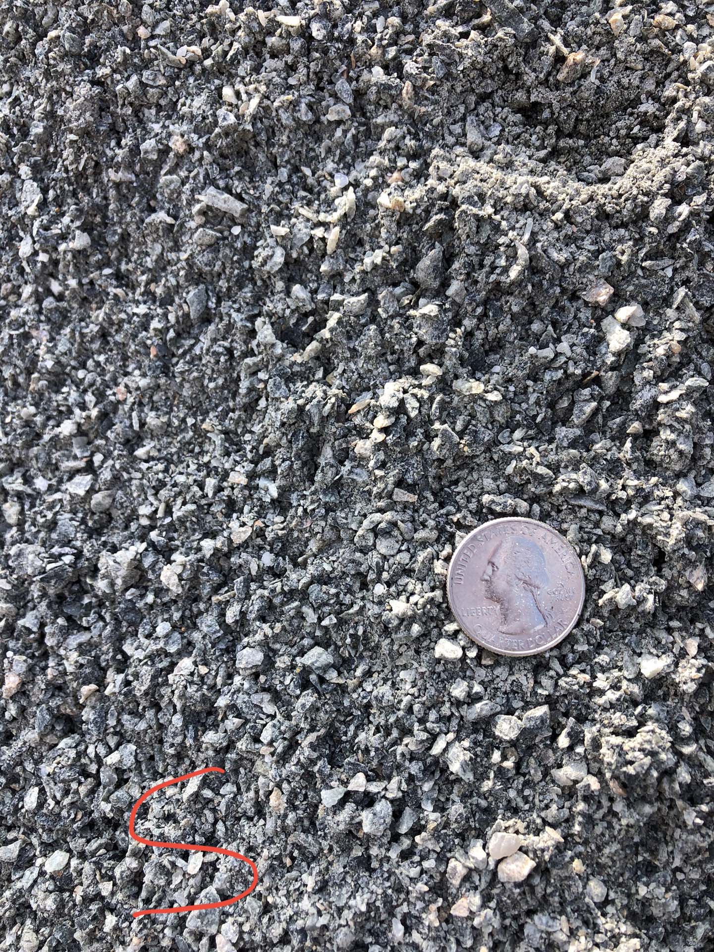 coin next to a pile of dark, small stones.